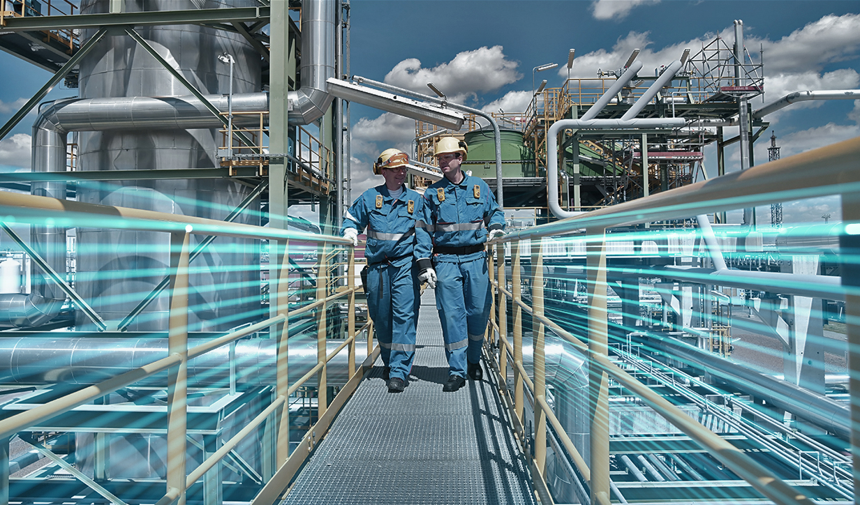 Two men in hardhats walking on an oil rig gantry